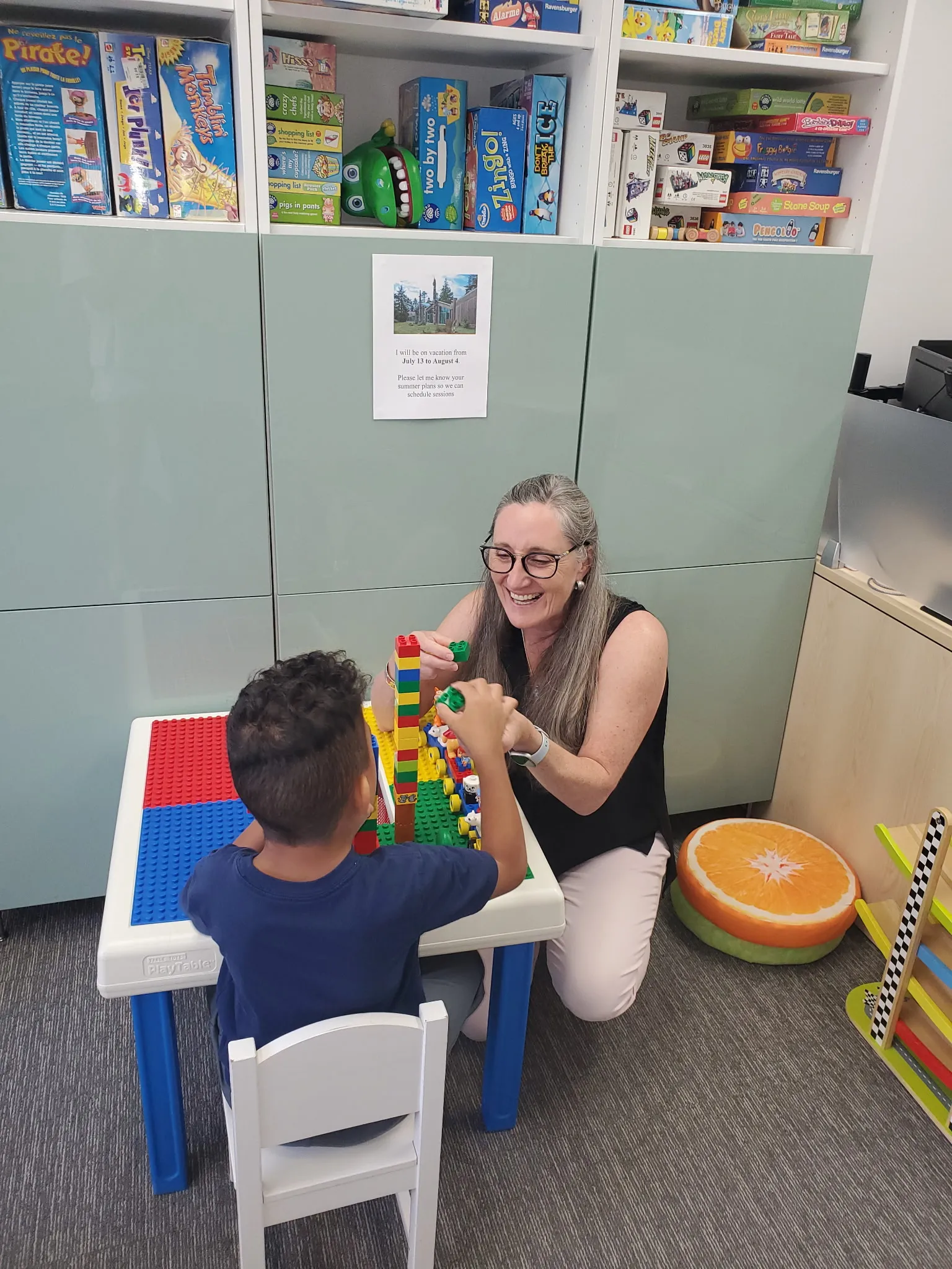 A therapist and child playing with Lego at a small table